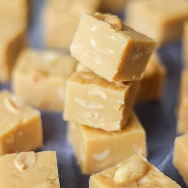 A tray of set peanut butter fudge, with three pieces in a tower.