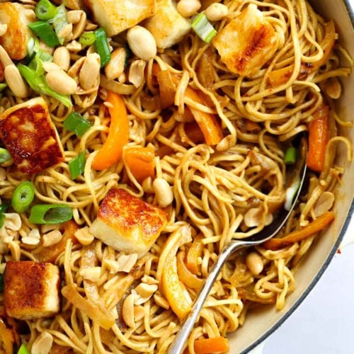 A fork in a big pan of noodles with halloumi and satay sauce for Peanut Butter Noodles.
