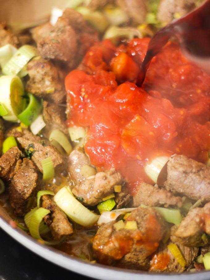Fried pork and leeks with tinned tomatoes added in a frying pan