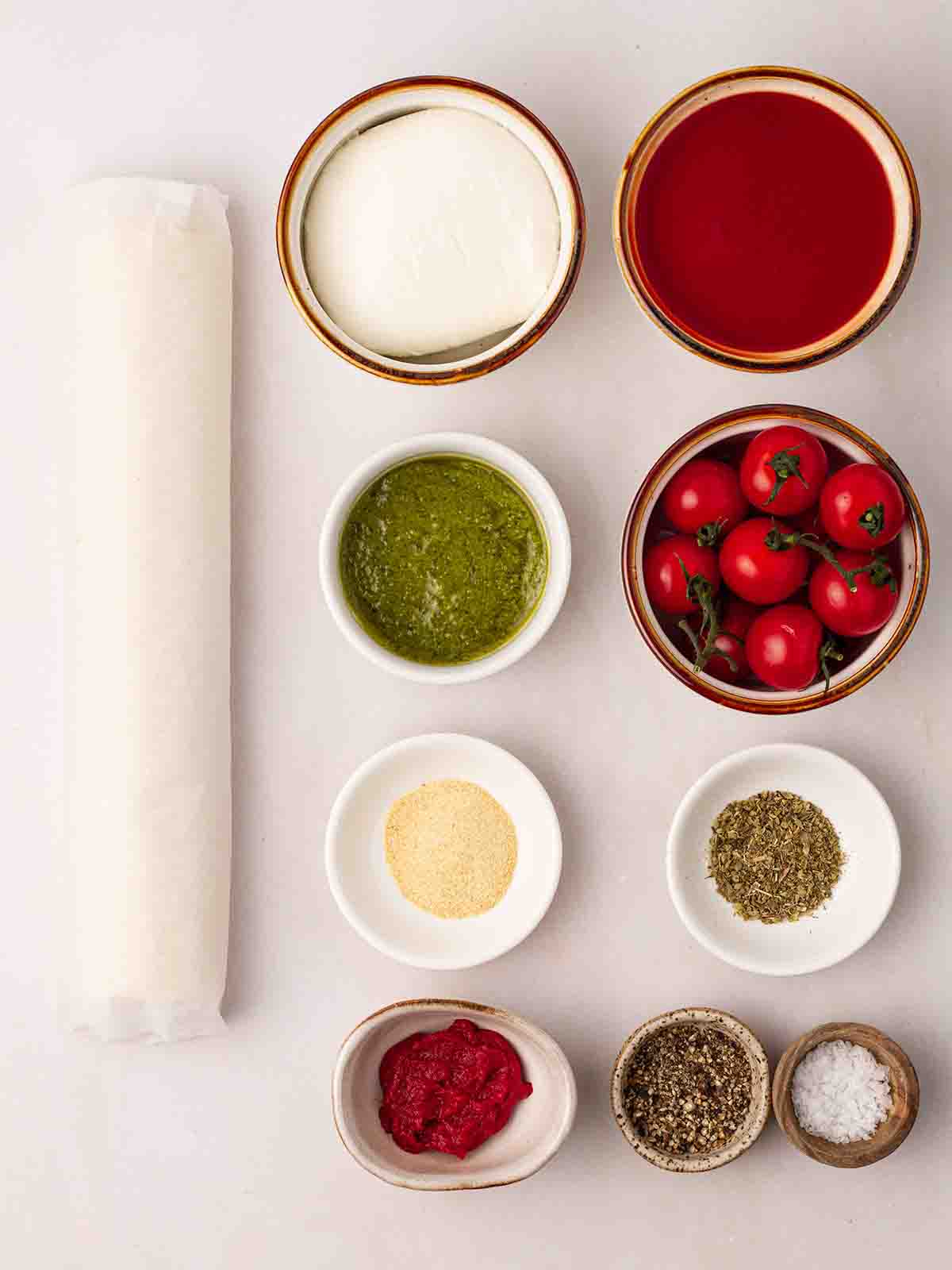 The ingredients for making Puff Pastry Pizza laid out in bowls on a white counter.