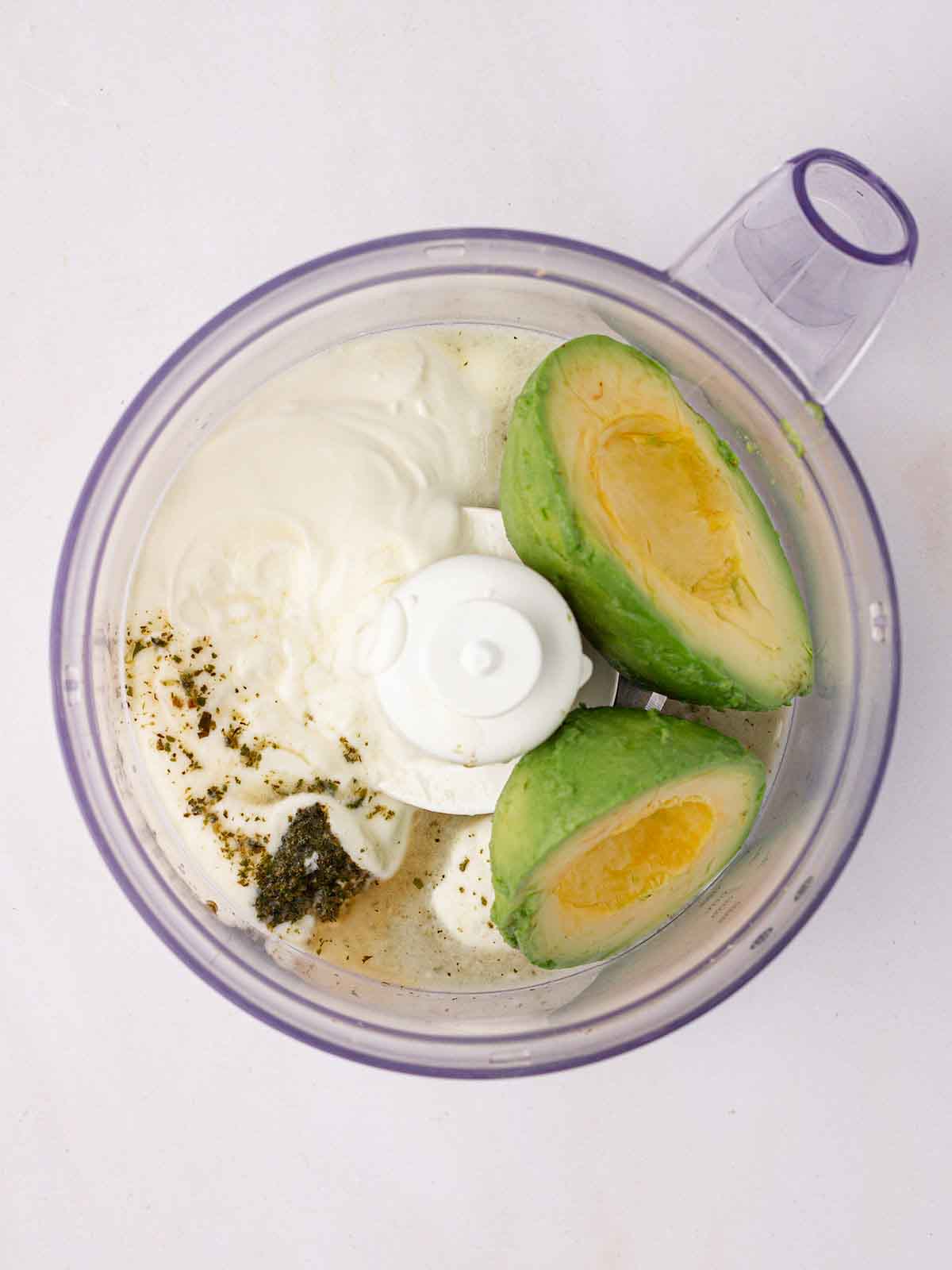 An avocado in a blender with yoghurt and mint sauce for step 2 in the recipe for Salmon Tacos.
