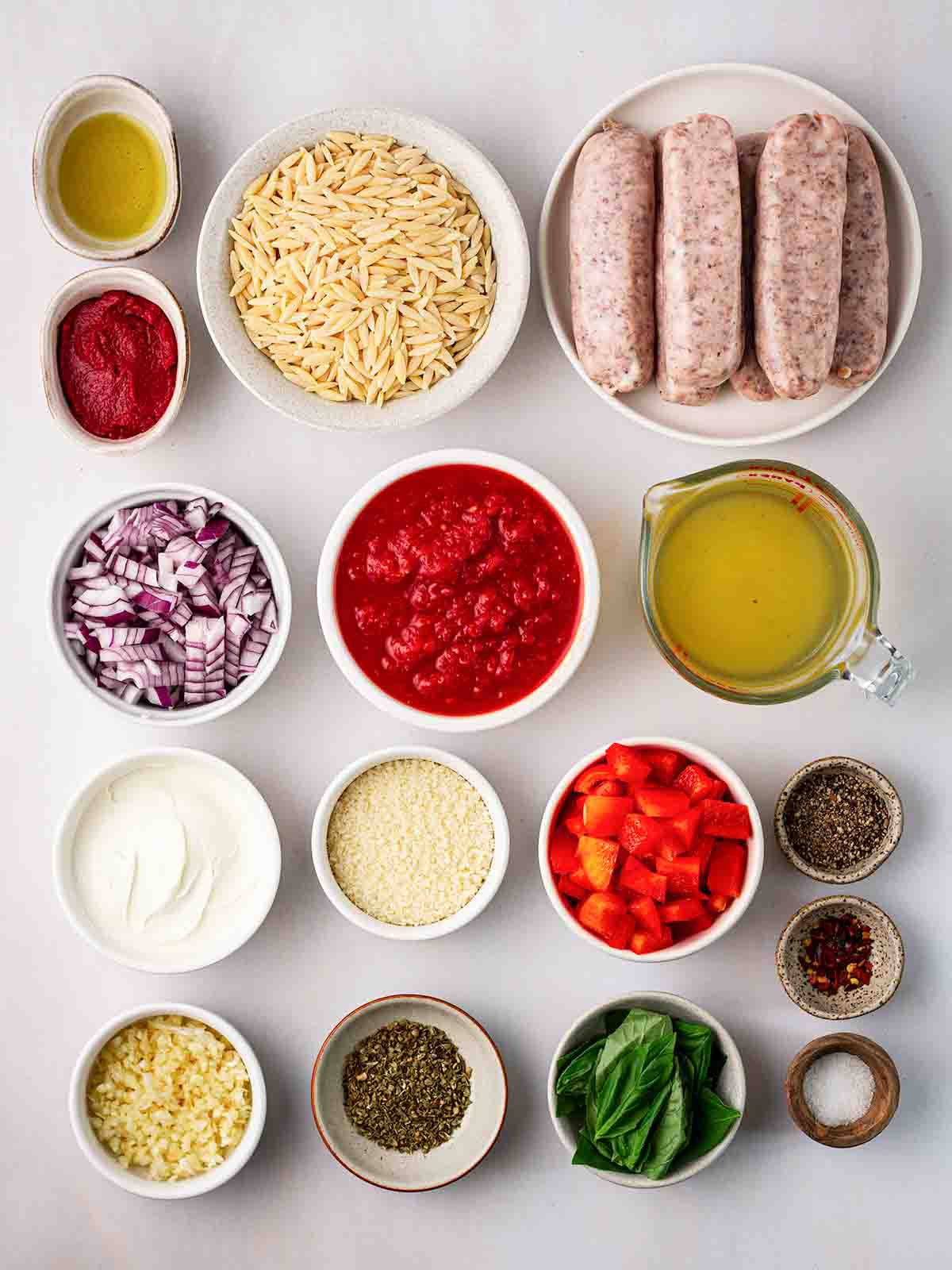 Ingredients for Sausage Orzo laid out on a counter top in small bowls.