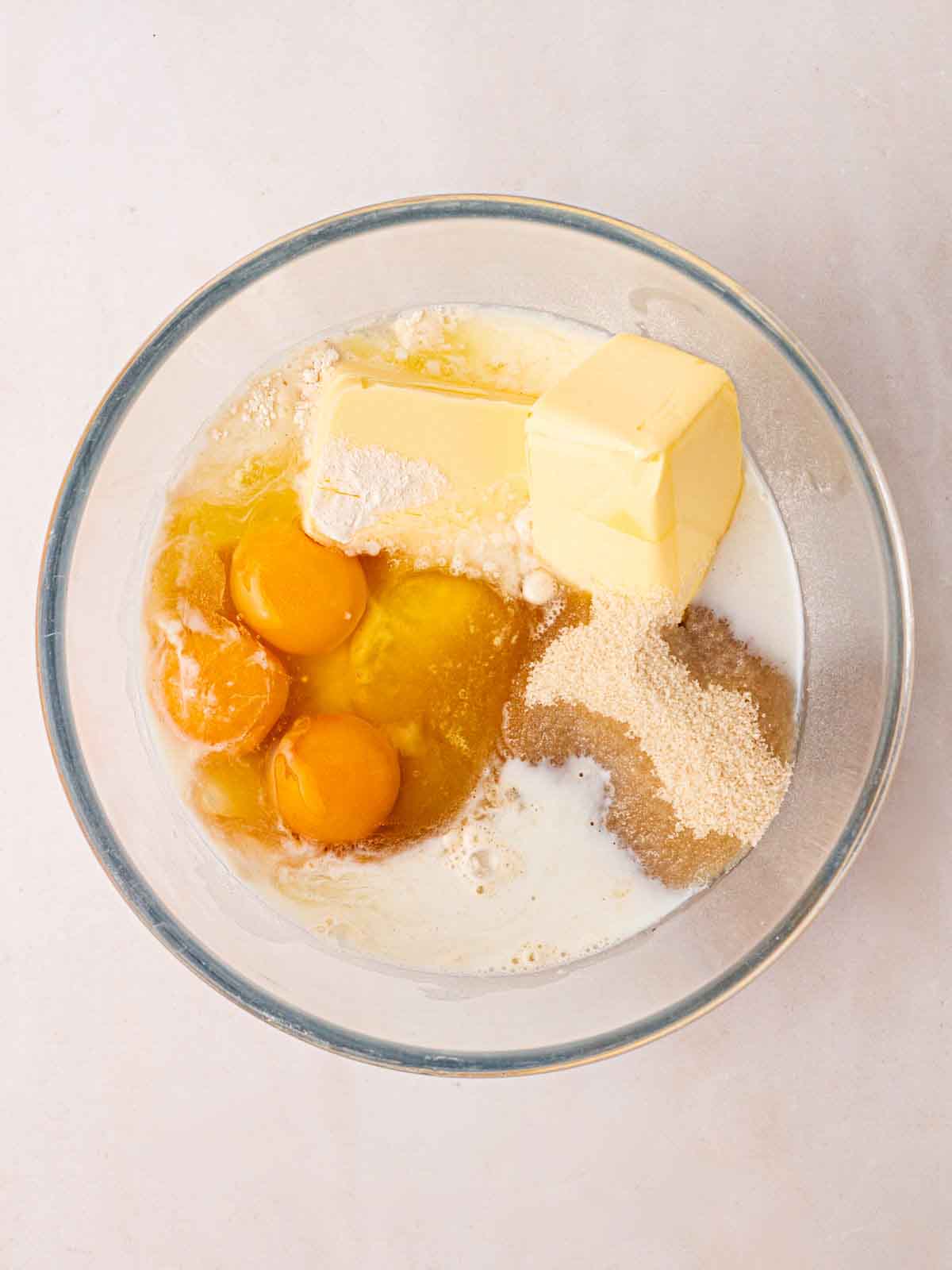 Butter, eggs, milk and sugar in a glass bowl ready to be mixed up to make a cake.