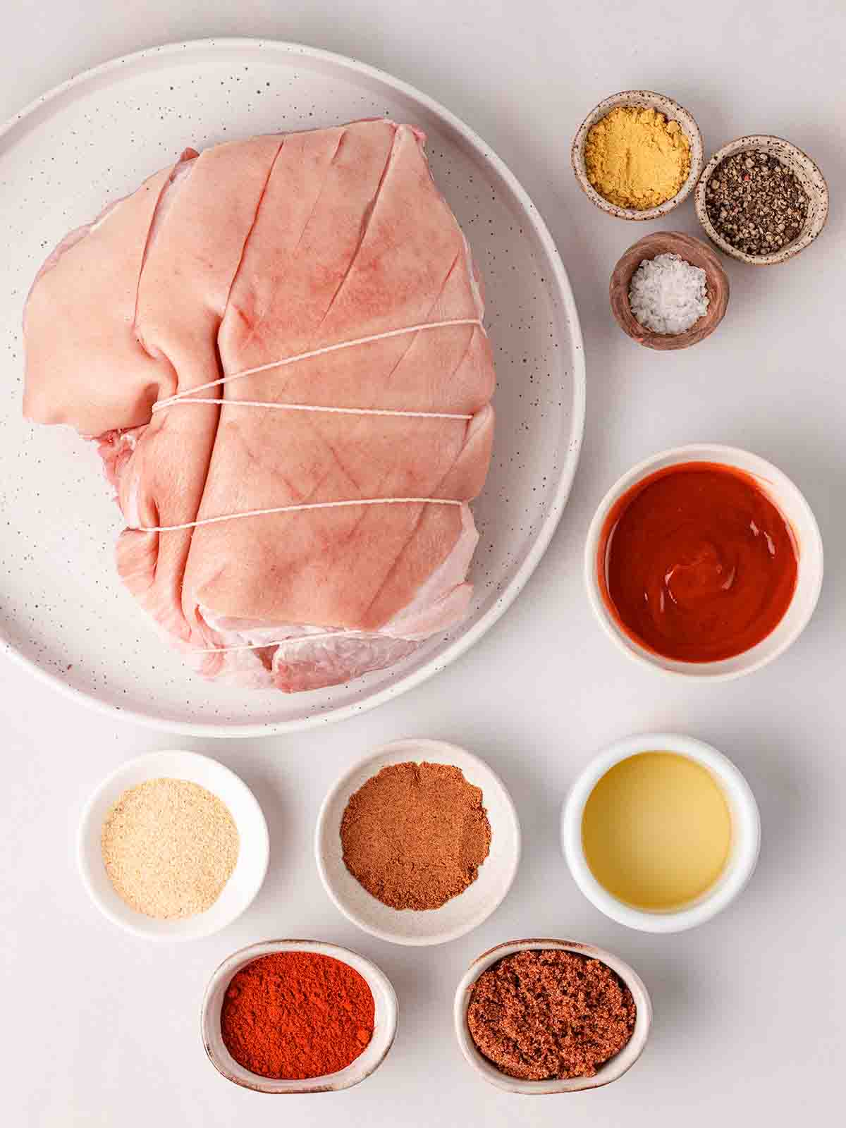 The ingredients for making slow cooker pulled pork, laid out on a white counter before cooking.