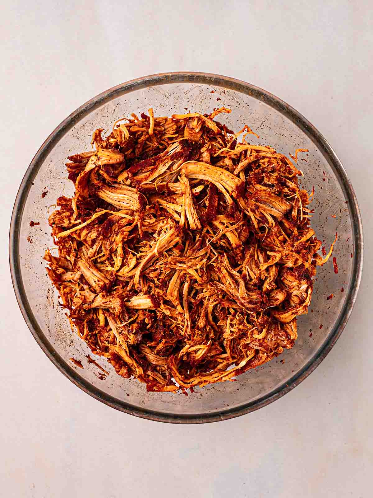 A bowl filled with cooked pulled pork, shredded and ready to serve.