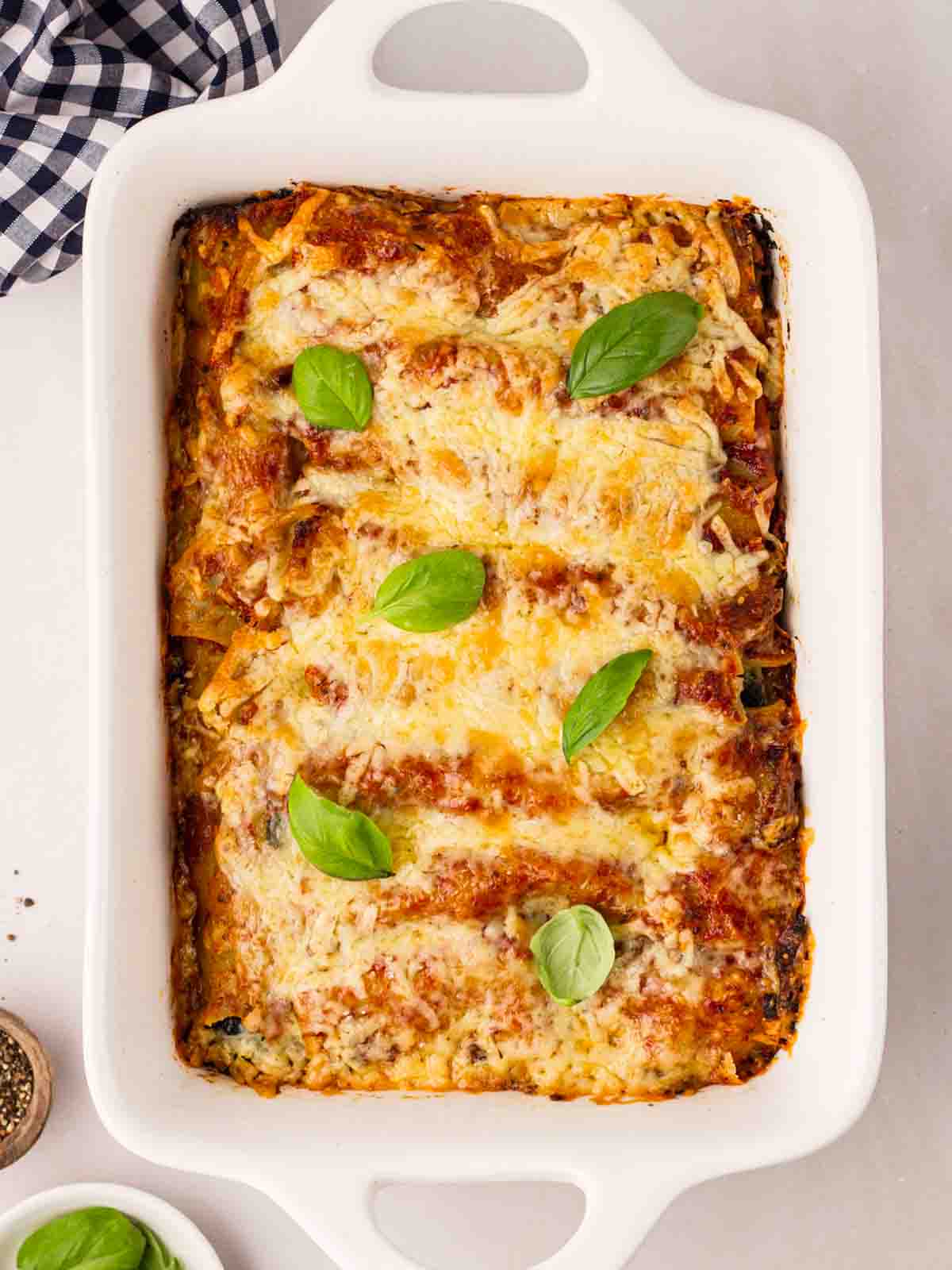 A just-baked Spinach and Ricotta Cannelloni in a white dish, ready to be served.