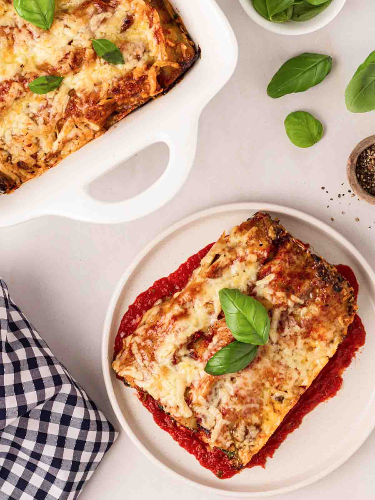 A portion of Spinach and Ricotta Cannelloni on a white plate, with the rest of the dish to the side.