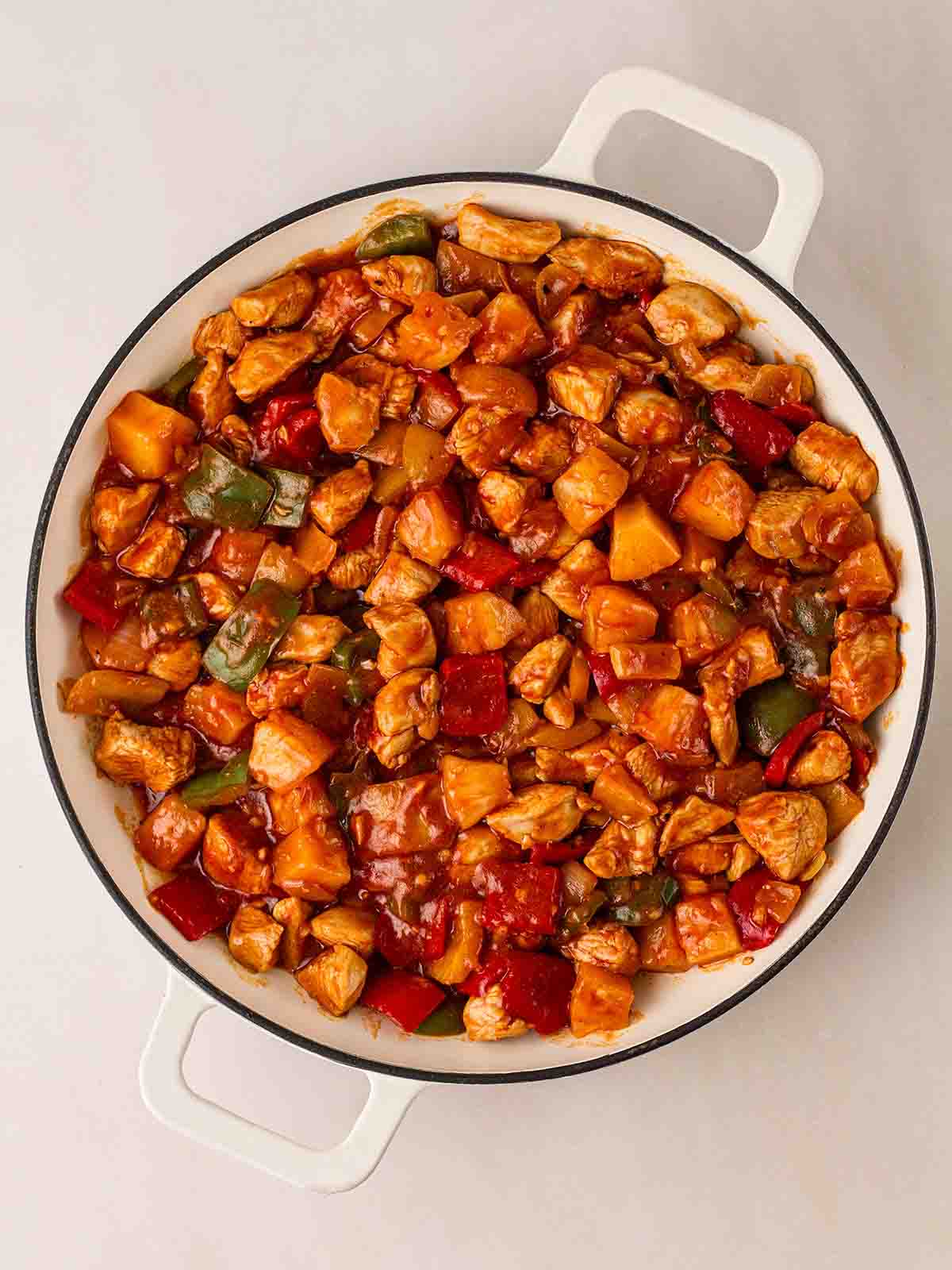 A large white pan filled with cooked Sweet and Sour Chicken dish.
