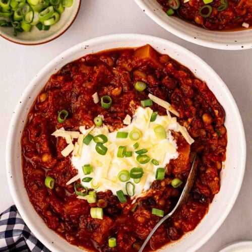Two bowls of veggie chilli on a white table.