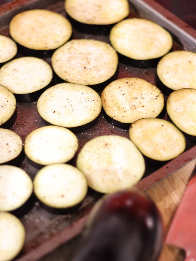 Slices of aubergine on a baking tray sprayed with oil. How to make Vegetarian Moussaka, step 3.
