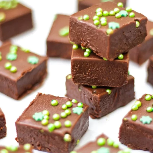 Piles of Baileys Fudge squares on a white table, with green sprinkles on top.