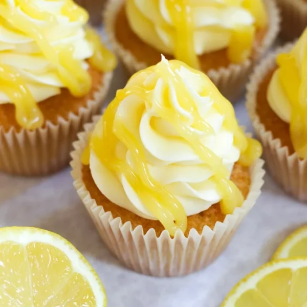 Lemon Cupcakes on a table with lemon frosting and lemon curd drizzled over the top.