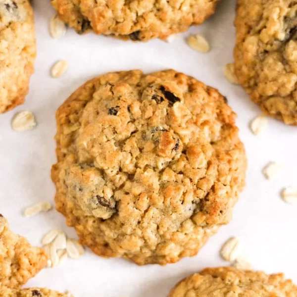 A close up of a single Oat Cookie on a baking tray with other cookies around it, straight out of the oven.