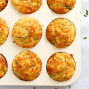 Cheese and sweetcorn savoury muffins in a muffin tin, just baked and golden on top.